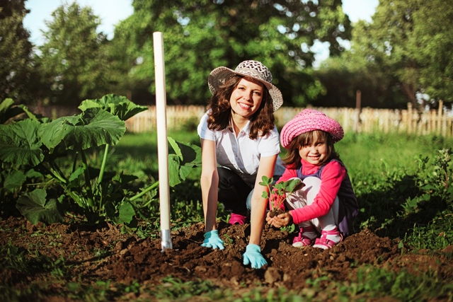 Mama in hči uživata pri opravili za njun zelenjavni vrt