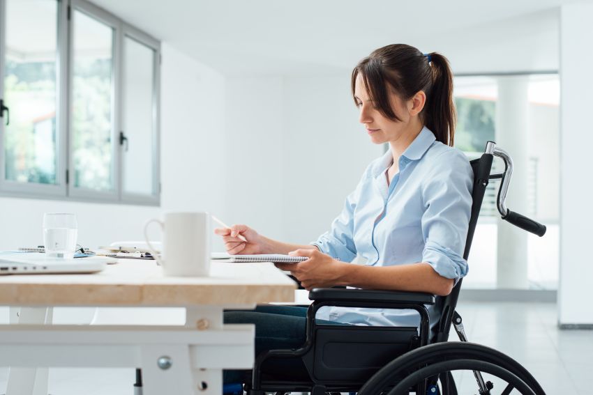 Mlada ženska v vozičku. Simbolna fotografija za prilagoditev življenja zaradi invalidnosti