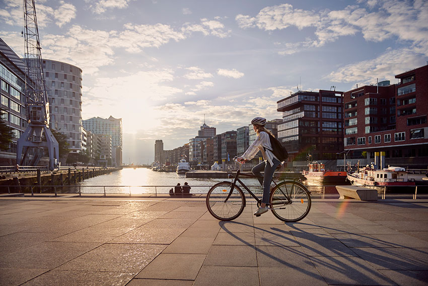 Mestno kolo - Dekle na mestnem kolesu raziskuje pristaniško mesto ob sončnem zahodu.