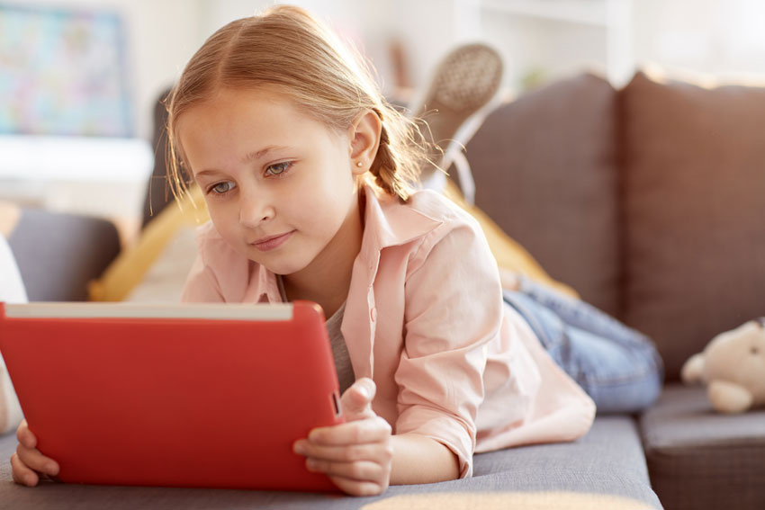 Deklica na tablici brska po internetu. Simbolna slika za varno rabo interneta med otroki