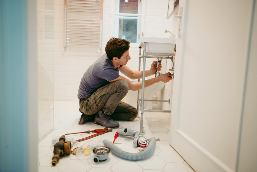 Obrtnik vodoinštalater za popravilo sifona v kopalnici - simbolna slika za pomoč obrtnika na domu