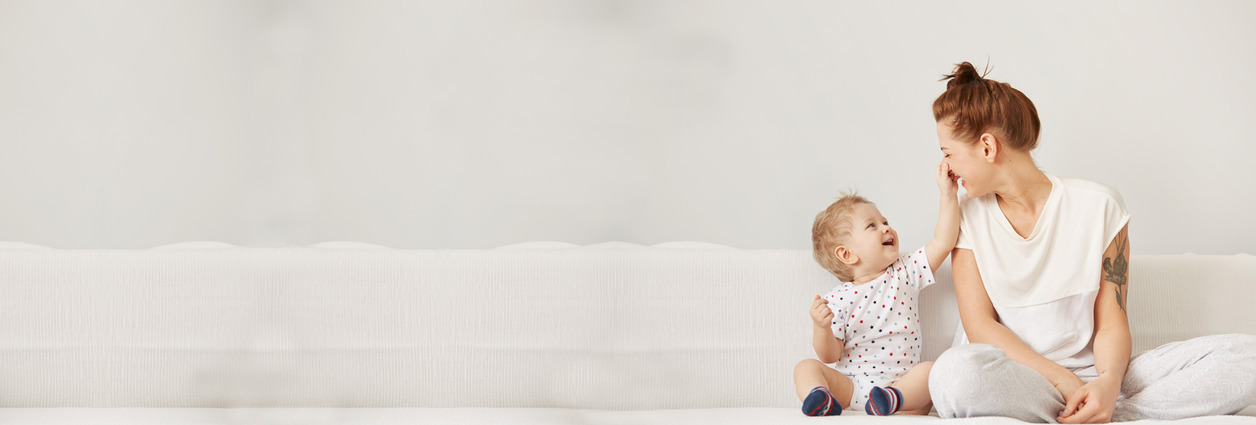 Mama z malčkom sedi na postelji in se zabava
