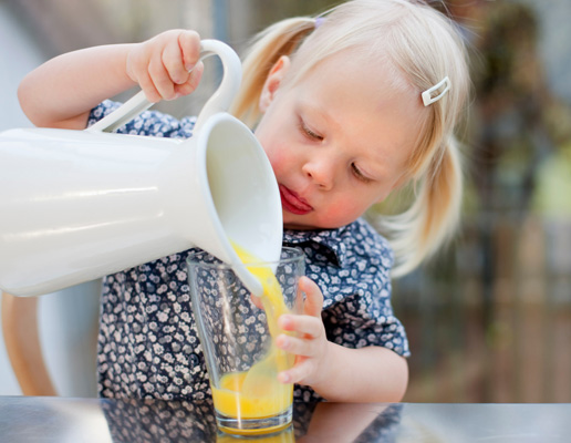 Malčica samostojno toči sok iz vrča