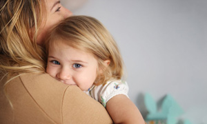 Mlada deklica nagajivo kuka čez mamino ramo