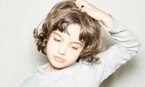 Deček se praska po glavi zaradi naglavnih uši