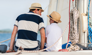 Oče in sin s poletnimi klobuki na obali v marini