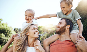 Mlada starša nosita vsak na ramenih enega majhnega otroka.