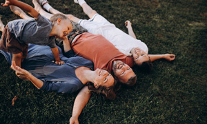 Mlad par z dvema otrokoma leži na travniku in uživa v mirnem trenutku