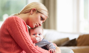 Mlada mamica otožno objema dojenčka