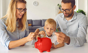 Starša z malčkom dajeta kovance v hranilnik