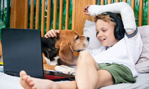 Deček z roko v mavcu leži na postelji, družbo mu dela kuža