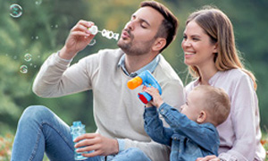 Mlada družina na pikniku piha milne mehurčke