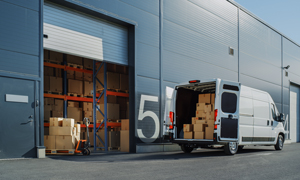 Transportni kombi pred skladiščem prevzema pakete izdelkov za transport