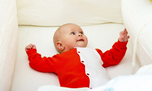 Ljubek dojenček leži v posteljici in opazuje okolico