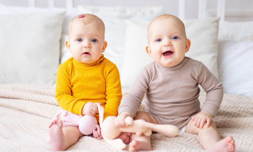 Dva dojnčka sedita en ob drugem - en ima na čelu jagodno znamenje