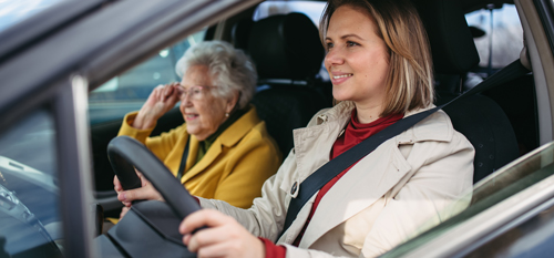 Fotografija mlajše ženske, ki starejšo gospo pelje na pregled - simbolna uprizoritev prehodne oskrbe zaradi nezgode ali bolezni