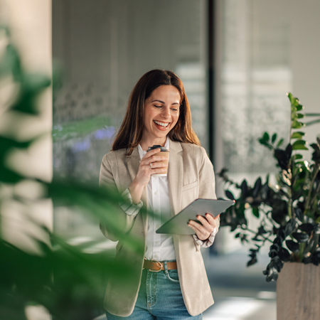 Mlada zaposlena v poslovnem okolju, s kavo in tabličnim računalnikom