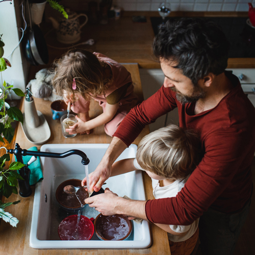 Oče z majhnima otrokoma v lastnem domu pripravlja zajtrk