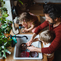 Oče z majhnima otrokoma v lastnem domu pripravlja zajtrk