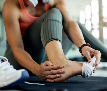 Tekačica si po treningu sezuva športne čevlje in nogavice, saj si zaradi bolečin želi ogledati stopalo.