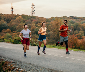 Tekačica kleči in si zavezuje športne copate.