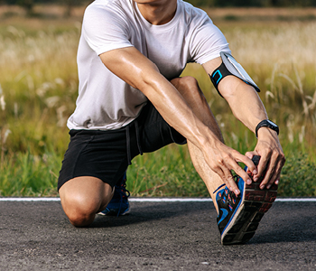 Tekačica oblečena v poletno tekaško opremo po asfaltu teče čez prazno urbano parkirišče.