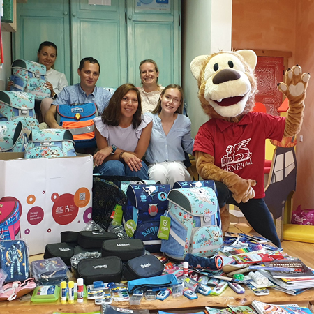 Skupina THSN ambasadorjev s predstavniki ZPM in Generalijevim levčkom ob predaji šolskih torb in drugih potrebščin