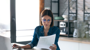 Podjetnica zbrano pregleduje zavarovalno polico, ki jo bo ščitila pred finančnimi težavami v primeru izgube dohodka.
