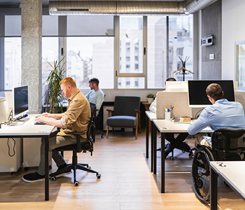 Skupina mladih samozaposlenih med delom v coworking pisarni.