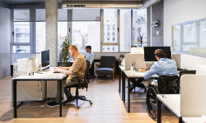 Skupina mladih samozaposlenih med delom v coworking pisarni.