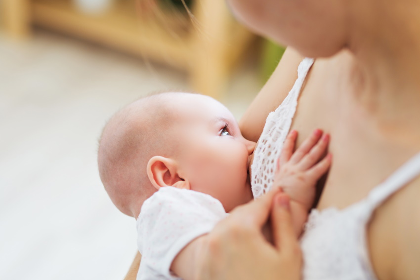 Prikupen dojenček se doji v materinem naročju, mama pa zaupa, da bo popil dovolj mleka