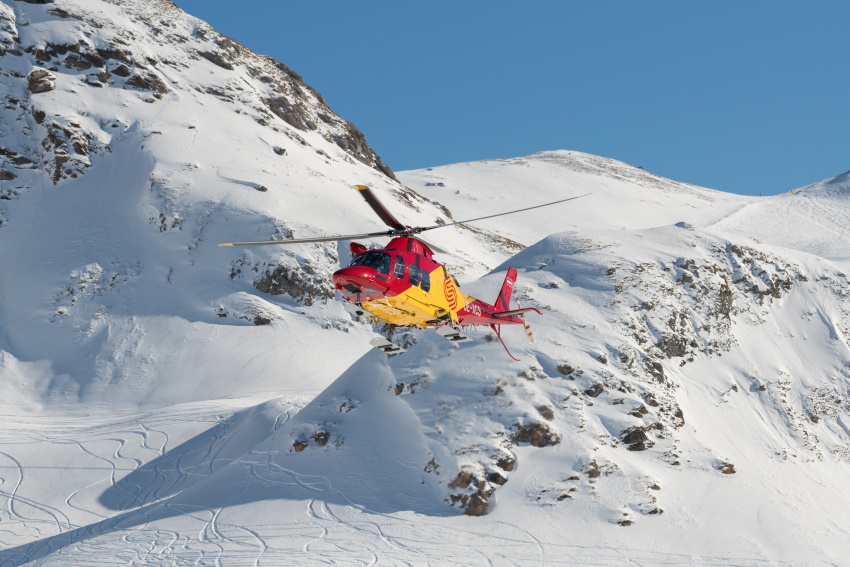 Avstrijski reševalni helikopter se pripravlja na prevzem poškodovanca na smučišču.