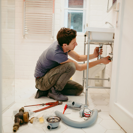 Mojster popravlja sifon v kopalnici