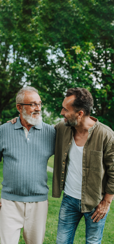 Oče in odrasel sin med sprehodom po urbanem parku v živahnem pogovoru