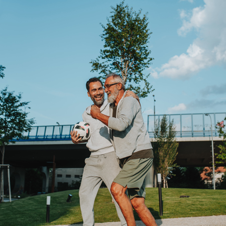 Starejši gospod se z odraslim sinom in nogometno žogo odpravlja na igrišče