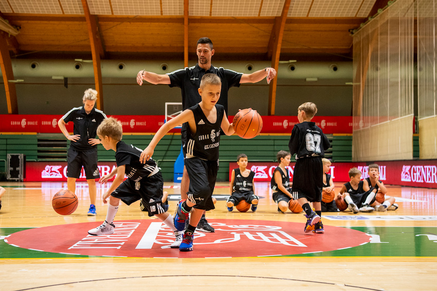 Košarskarski kamp Gorana Dragića zaposluje ekipo trenerjev, ki otrokom pomaga graditi njihove košarkarske spretnosti in še veliko več.